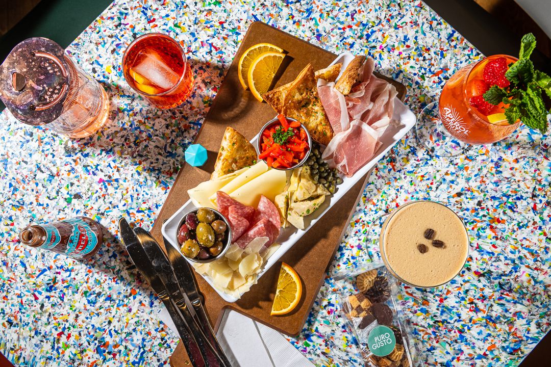 a speckled table with a charcuterie tray and aperitifs