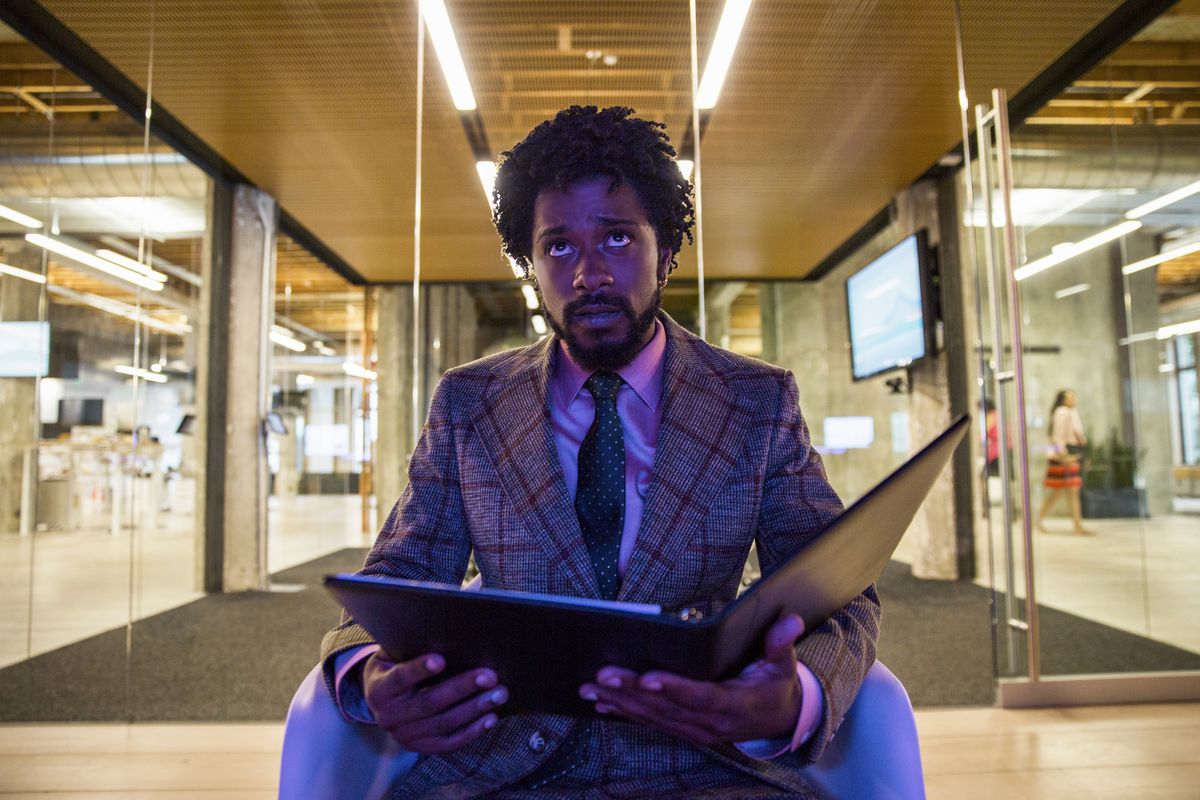 Lakeith Stanfield sits in a glass booth under purple lighting in Boots Riley’s SORRY TO BOTHER YOU.