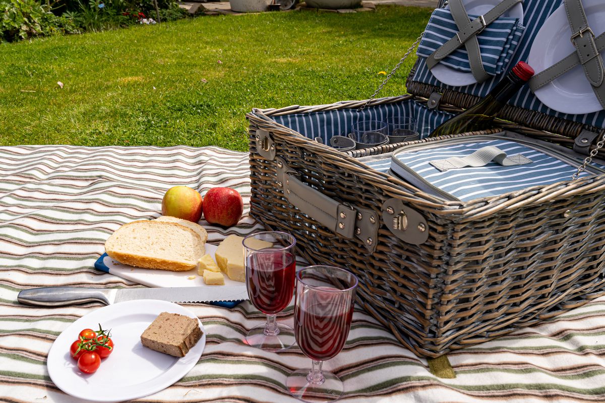 Picnic basket and food on a blanket outside