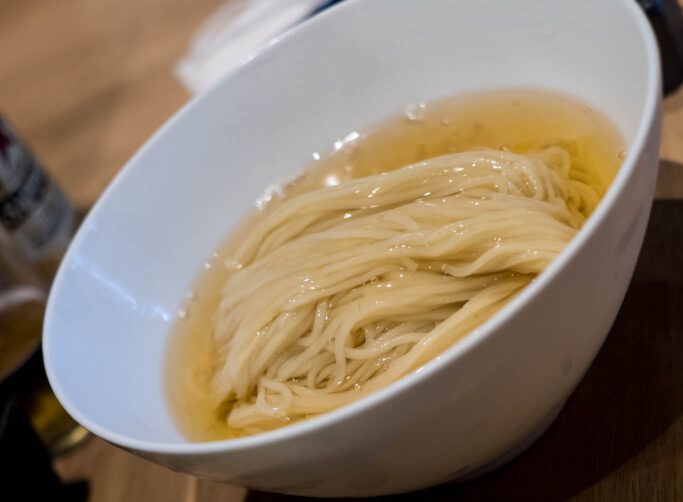 A bowl of noodles in broth.
