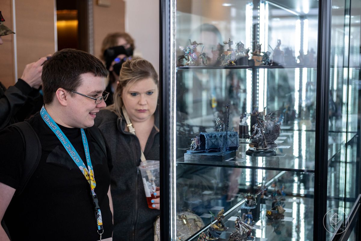 Fans, a man and a woman, admire the pieces on display at AdeptiCon 2023.