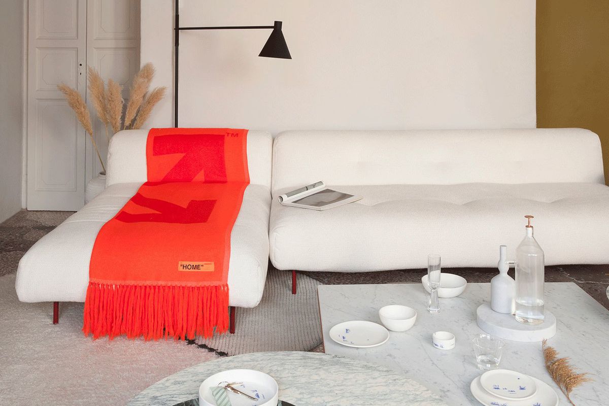 White couch with red throw and a smattering of plates and bowls.