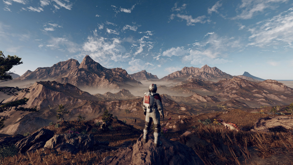 The player character stands on a hill, an entire range of mountains extending beyond.