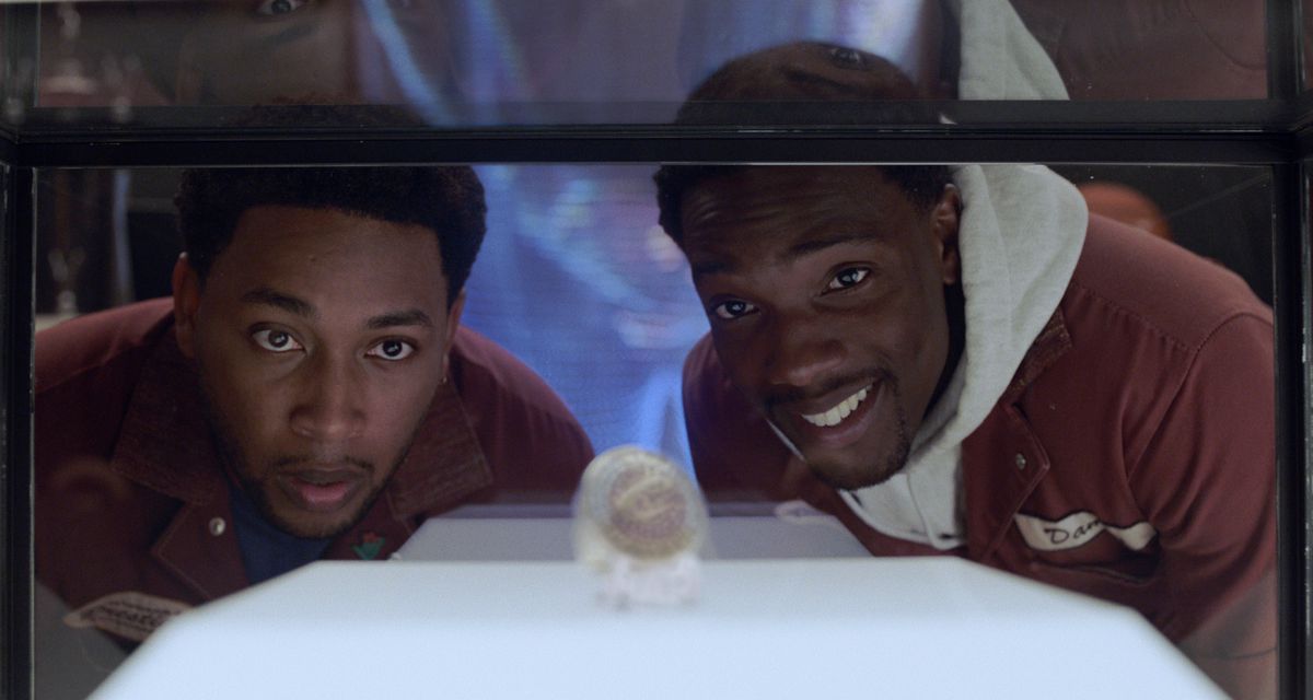The two stars of House Party look at one of LeBron James’s championship rings in a glass case in House Party.