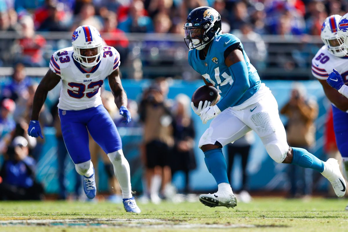 Jacksonville Jaguars running back Carlos Hyde (24) runs the ball while chased by Buffalo Bills defensive back Siran Neal (33) in the first half at TIAA Bank Field.