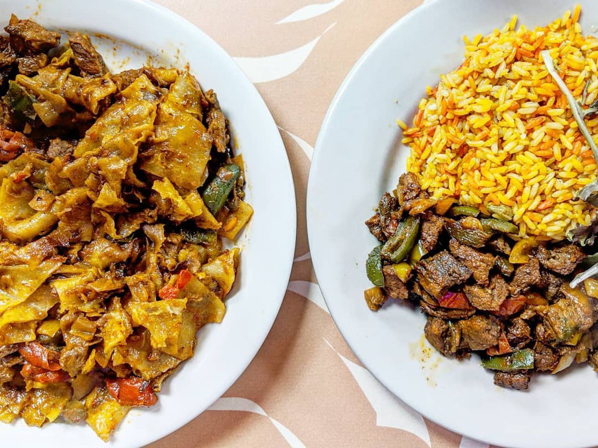 Overhead view of two Somali dishes on a pale peach tablecloth with white accents. One dish is chapati strips cooked in a tomato sauce with chunks of beef; the other is a beef biryani with multi-colored rice in shades of yellow and orange.