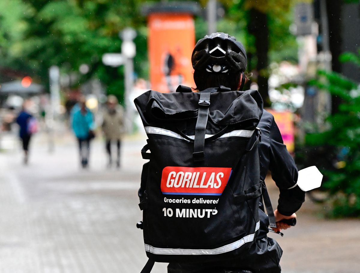 A courier of grocery delivery company “Gorillas” wears a backpack with the logo of the startup on his way to deliver purchases.