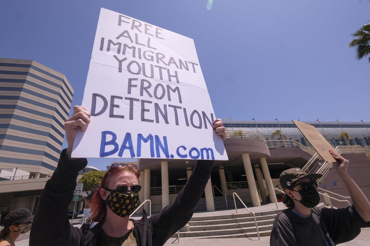 A demonstrator holds up a sign that reads, “Free all immigrant youth from detention. BAMN.com.”