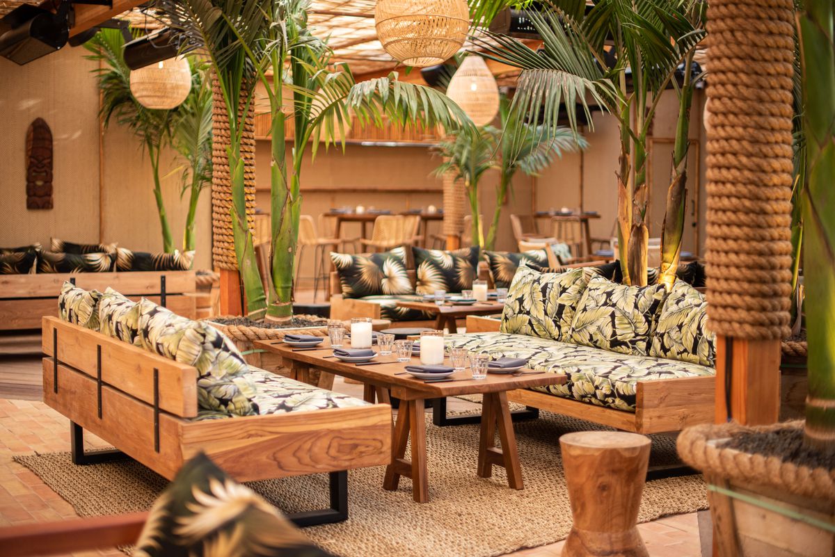 Belles Beach House main dining area with tropical trees and matching sofa decor.