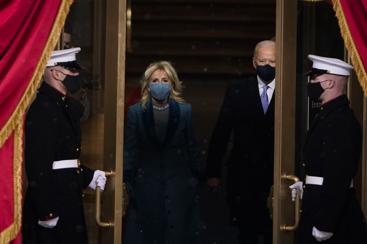 Joe Biden and his wife Jill walk out to the inauguration stage, with guards opening the doors.