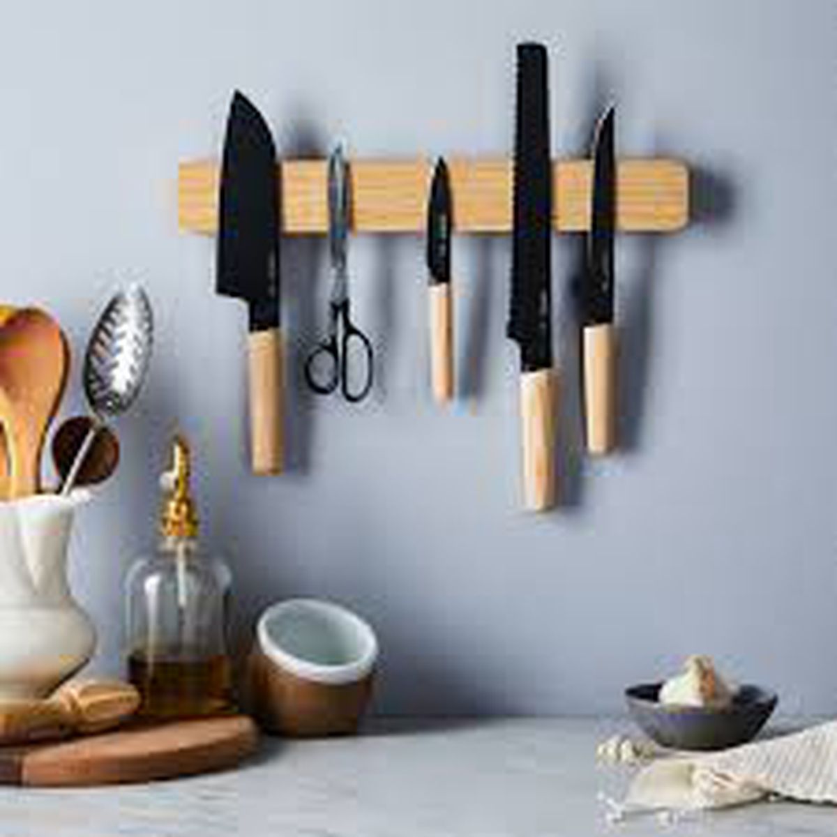 A wooden knife holder that is magnetic and hangs on the wall. Knives are held with the magnetic strip. 
