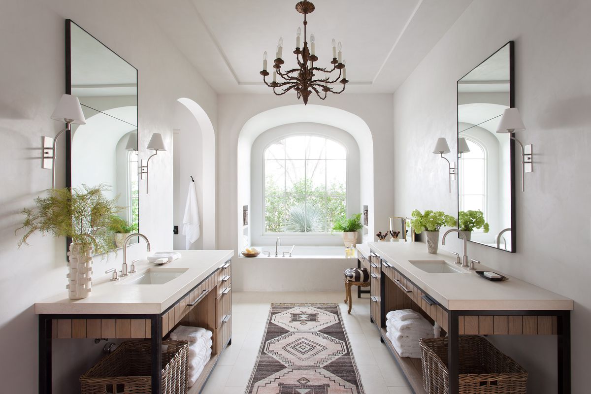 A primary bathroom with a traditional chandelier hanging over the tub.