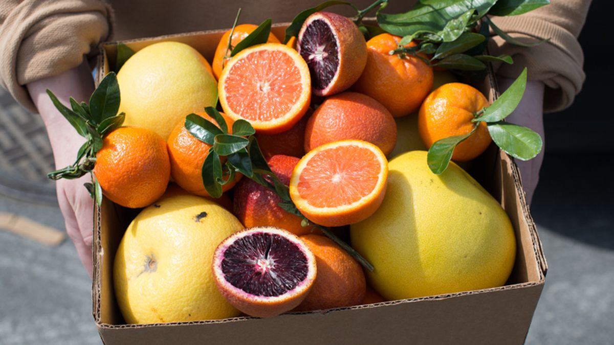 A box of whole and cut up oranges in pink and orange colors