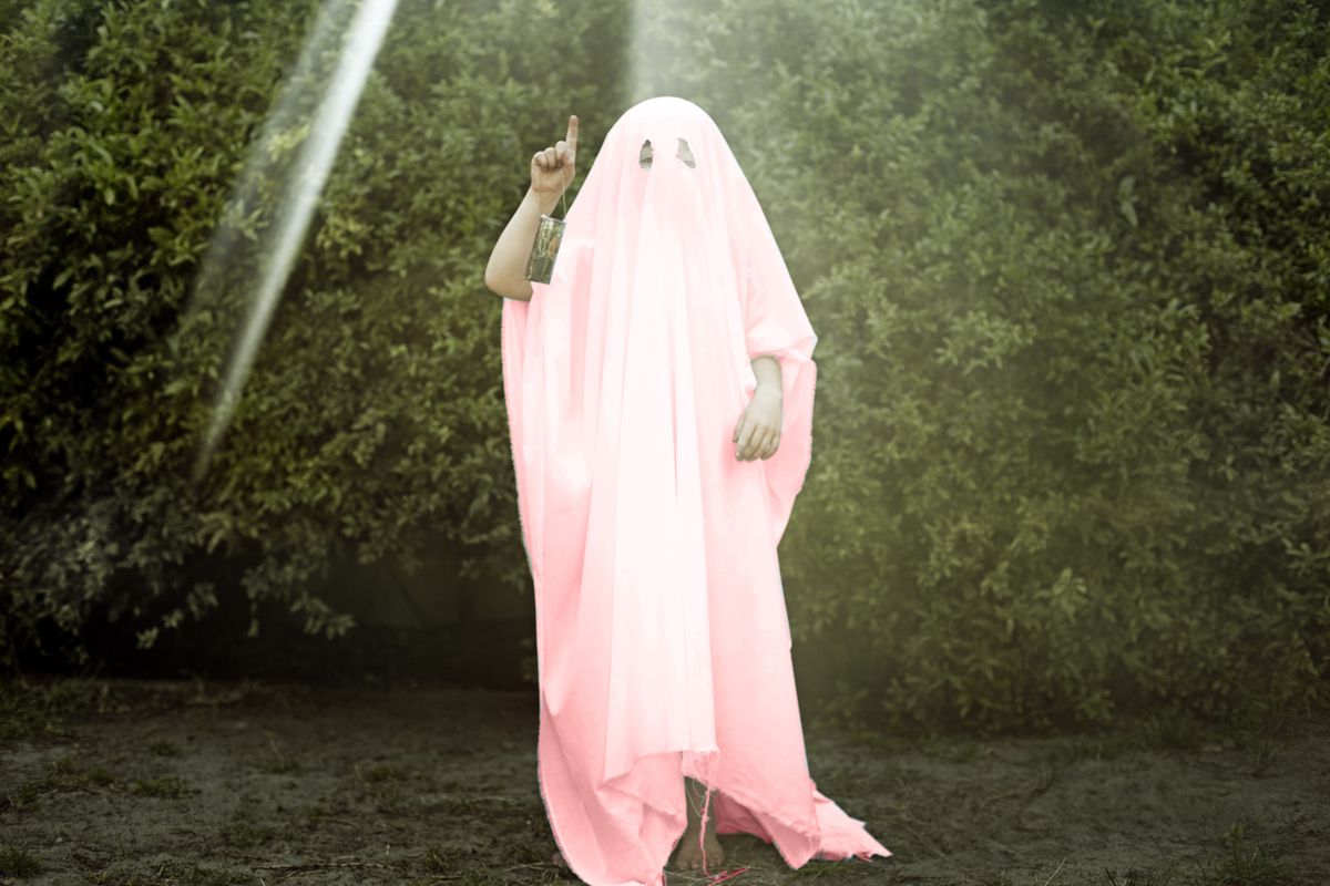 A person covered in a pink sheet as the ghost of millennial pink.