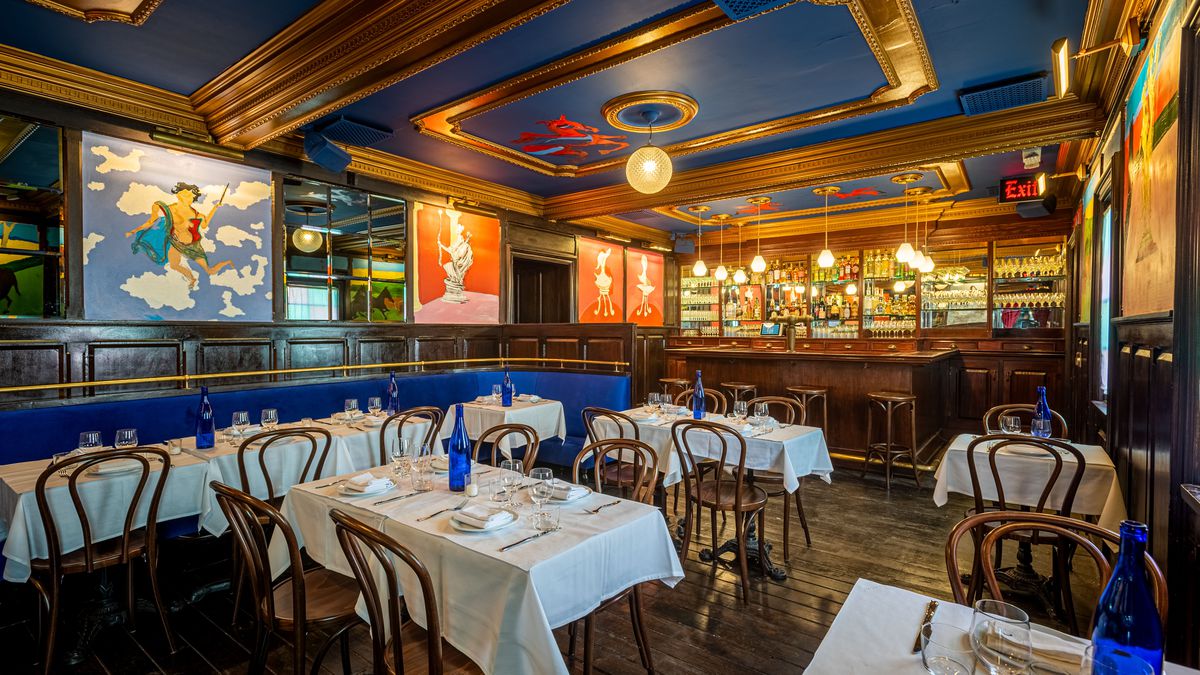 An old dining room with lots of colorful paintings of horses and deep blue walls with wooden ball at the back at Horses in Hollywood.