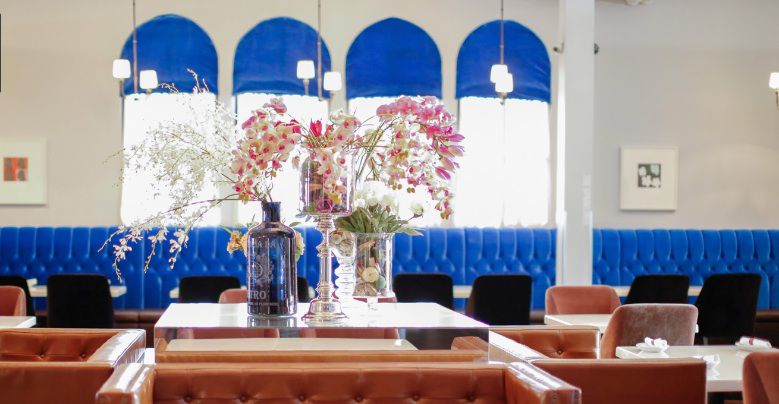 A dining room with blue booths and flowers