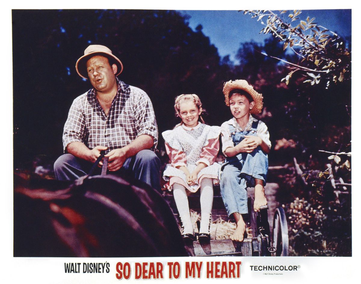 A 1948 lobby card for So Dear to My Heart, with Burl Ives, Luana Patten, and Bobby Driscoll sitting on a horse cart together