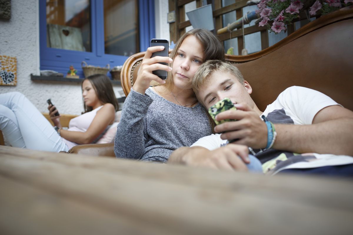 Three teens in a room, each looking at his or her phone