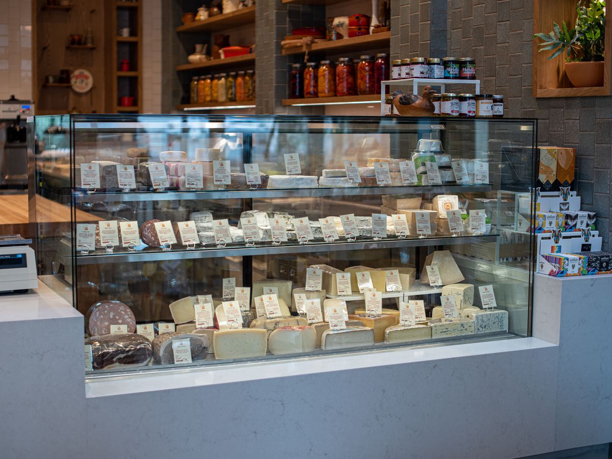 A glass case for cheeses of all sorts, complete with hand-written signs.