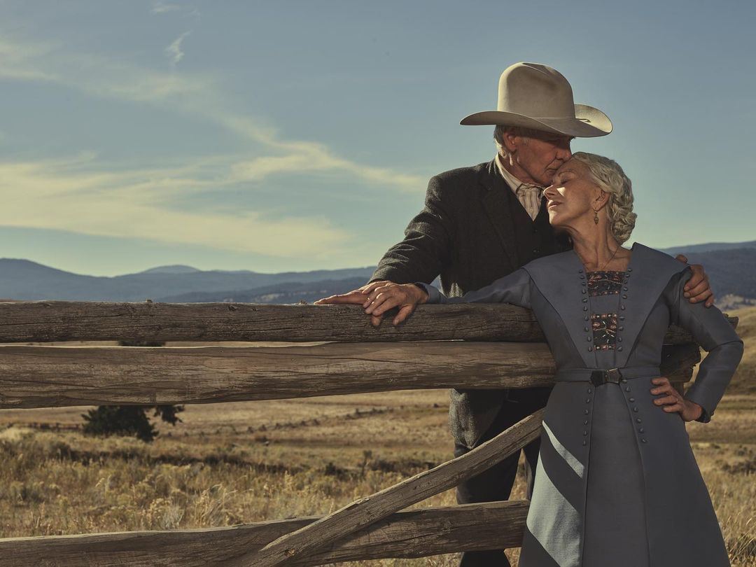 Harrison Ford and Helen Mirren in 1920’s era Western dress lean on a fence in the Montana countryside.