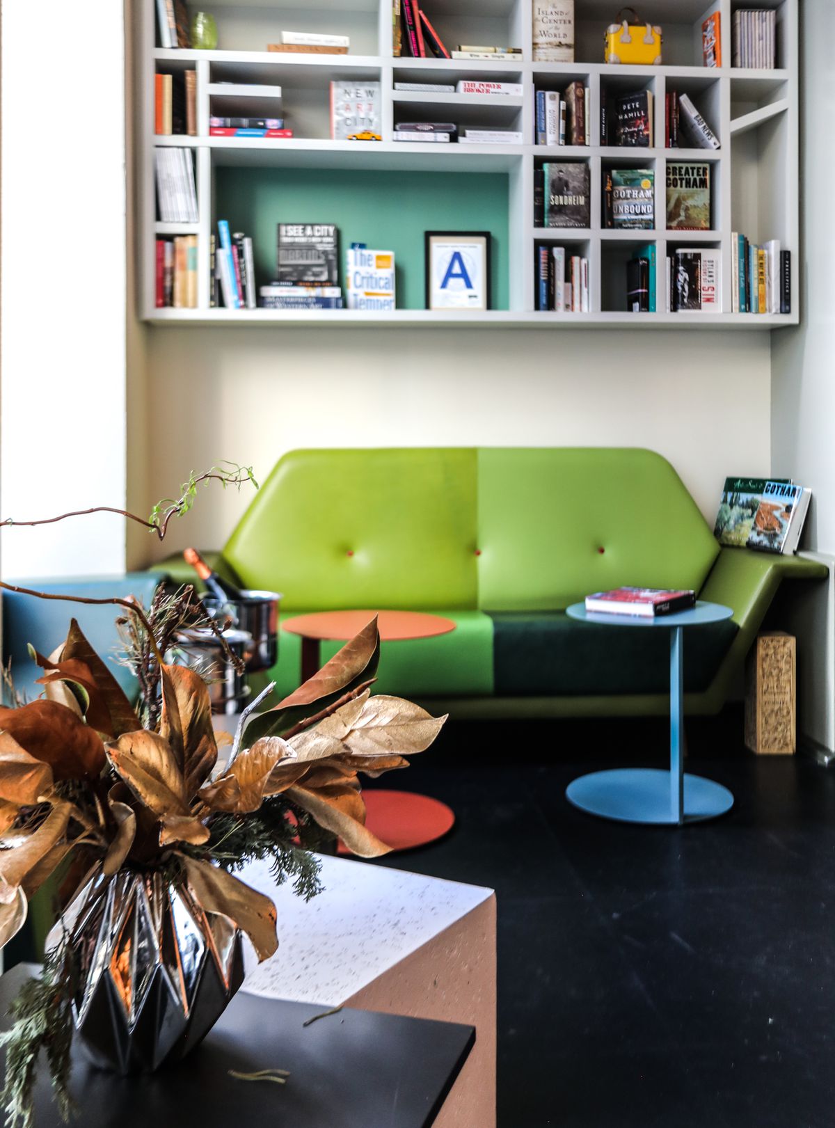 A library above a green loveseat.