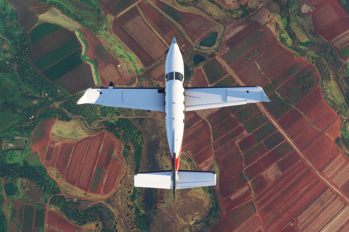 A plane flies over fields of colorful farmland in Microsoft Flight Simulator