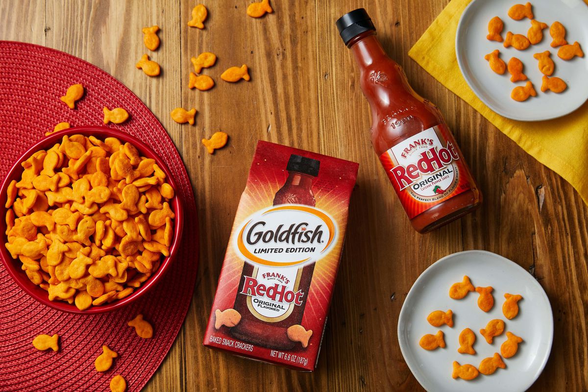 A top-down photo of Goldfish crackers in a bowl, a package of Goldfish, and a bottle of Frank’s RedHot sauce.