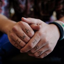 Freeman Stevenson poses for a photo at his father's home in Saratoga Springs on Friday, Dec. 2, 2016. On his fingers are tattooed "Ciwan Firat," the Kurdish nickname for his friend Jordan MacTaggart, who died fighting alongside Stevenson in Syria.