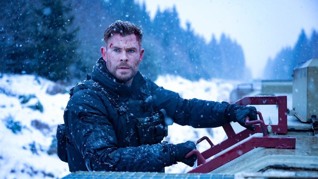 Chris Hemsworth in body armor riding on a train in the snow in Extraction 2