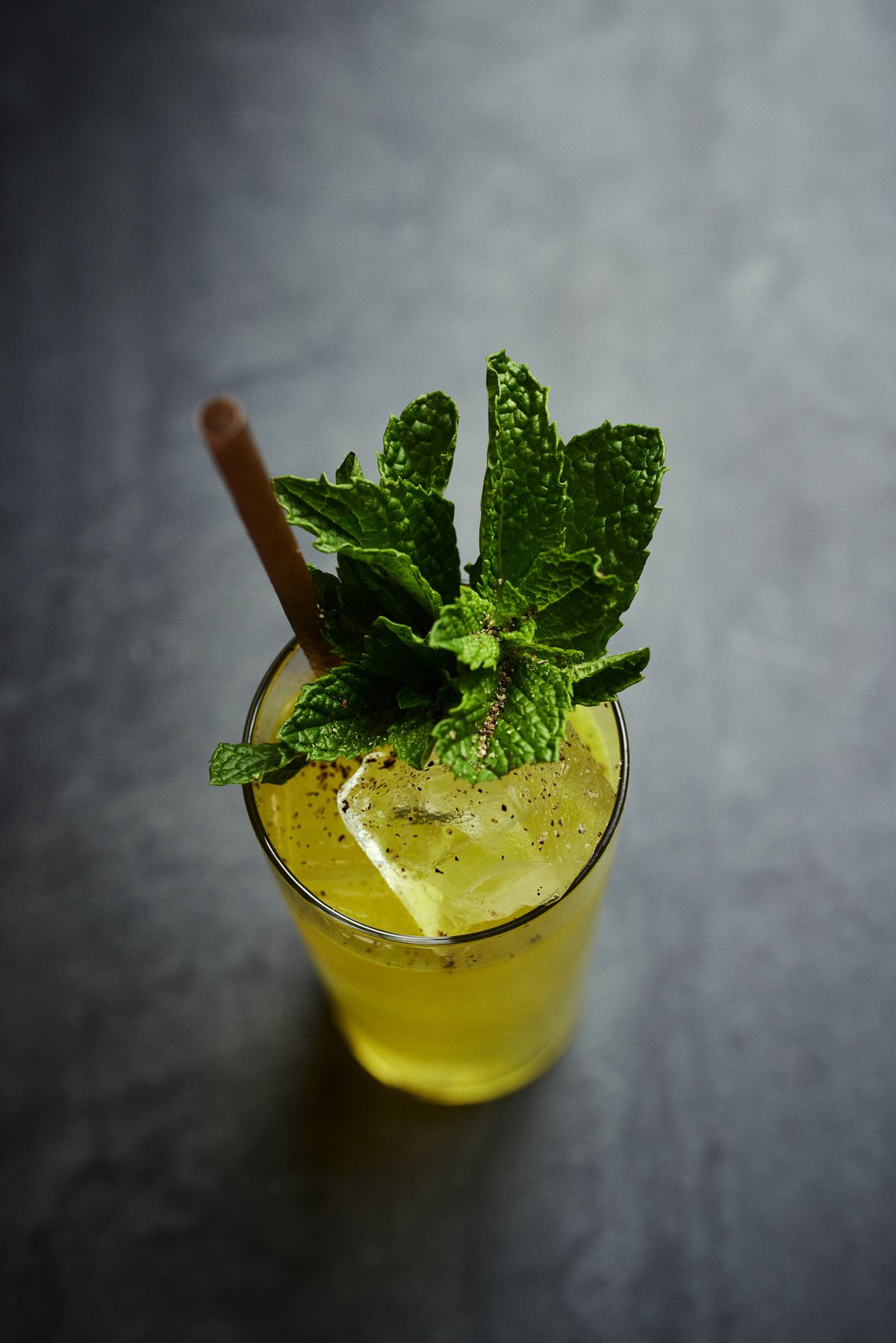 The Five Pointed Star, a yellow cocktail in a tall glass with mint garnish.