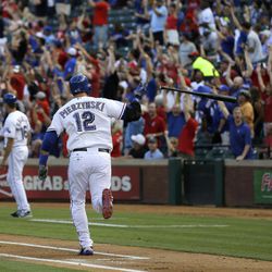 Fans stand and cheer as Texas Rangers' A.J. Pierzynski (12) flips the bat running down the first base line on his two-run home run off of Oakland Athletics starting pitcher Dan Straily in the second inning of a baseball game, Monday, June 17, 2013, in Arlington, Texas. 