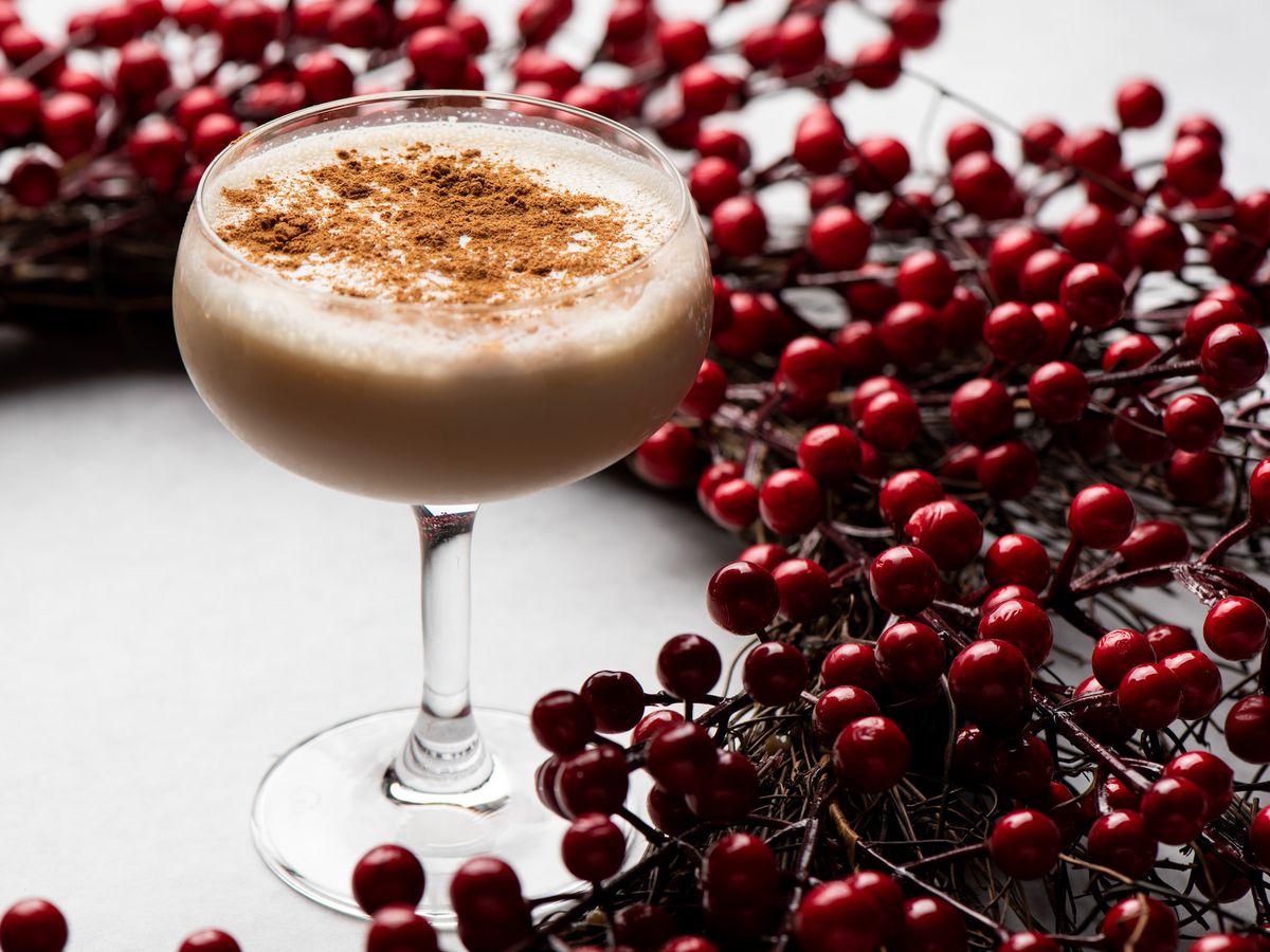 A coupe glass with nutmeg on top of a foamy cocktail for the holidays.