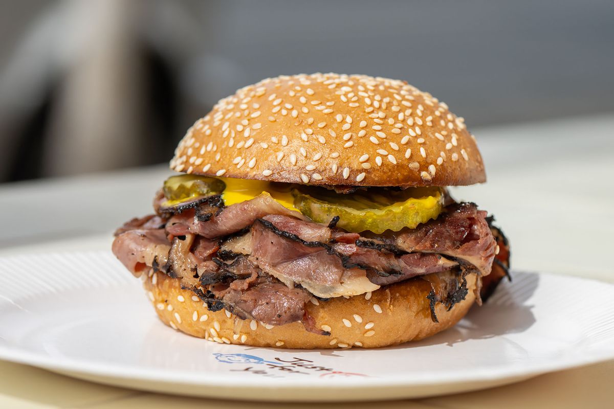 A seeded bun with thin shaved pastrami and thick shaved pickle and sauce.