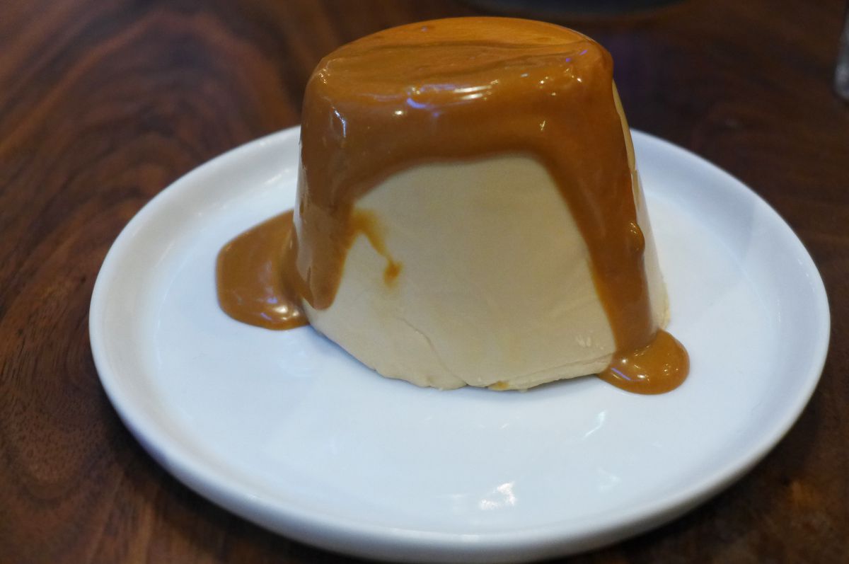 A button of pudding with brown sauce spilled over the top.