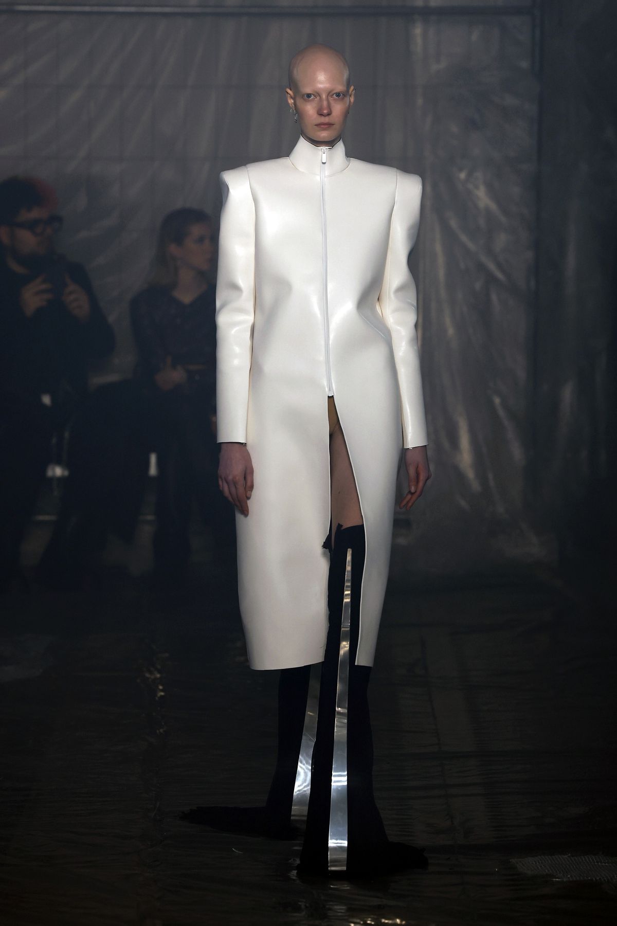A model wearing a long white leather coat and heels with sword-like protrusions walks the runway at the Han Kjobenhavn fashion show at Milan Fashion Week.