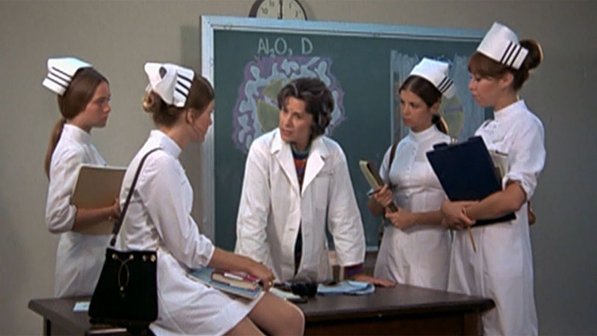 Nurses around a teacher and chalkboard in The Student Nurses