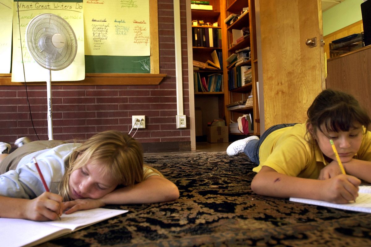 Darlene  Cisneros , 10, left, and Manuela  Ramirez , 10, of Harry M. Barrett Elementary School, Denver, Colo, is taking a note by the electric fan during the afternoon writing class on Tuesday afternoon in 2003.