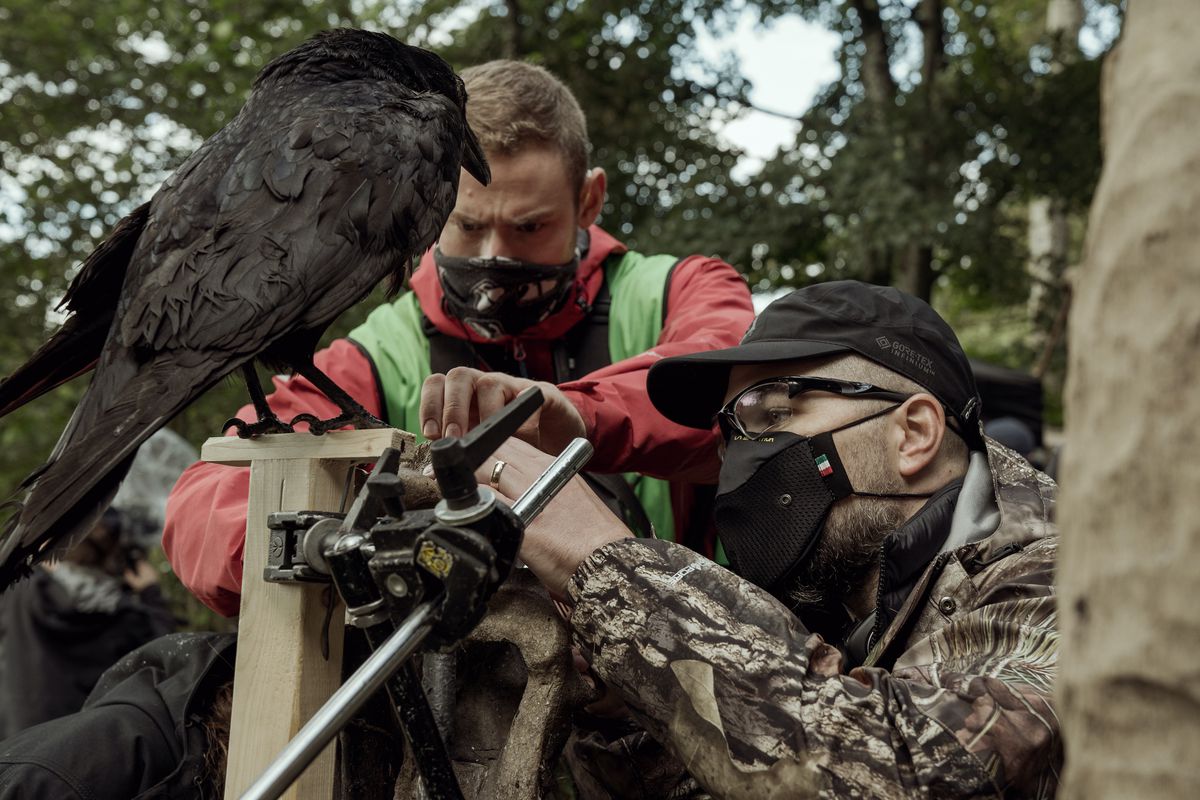 Robert Eggers, up close on set with a camera pointed at a live crow