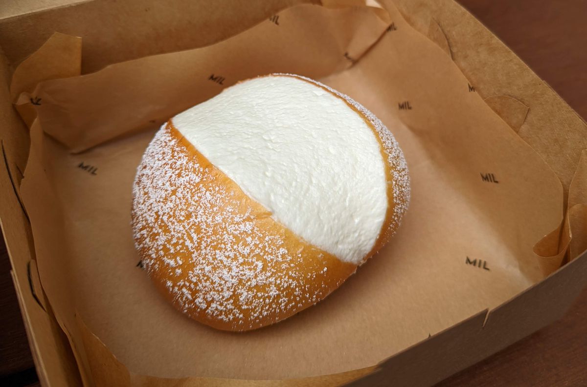 A soft bun filled with cream and topped with powdered sugar.