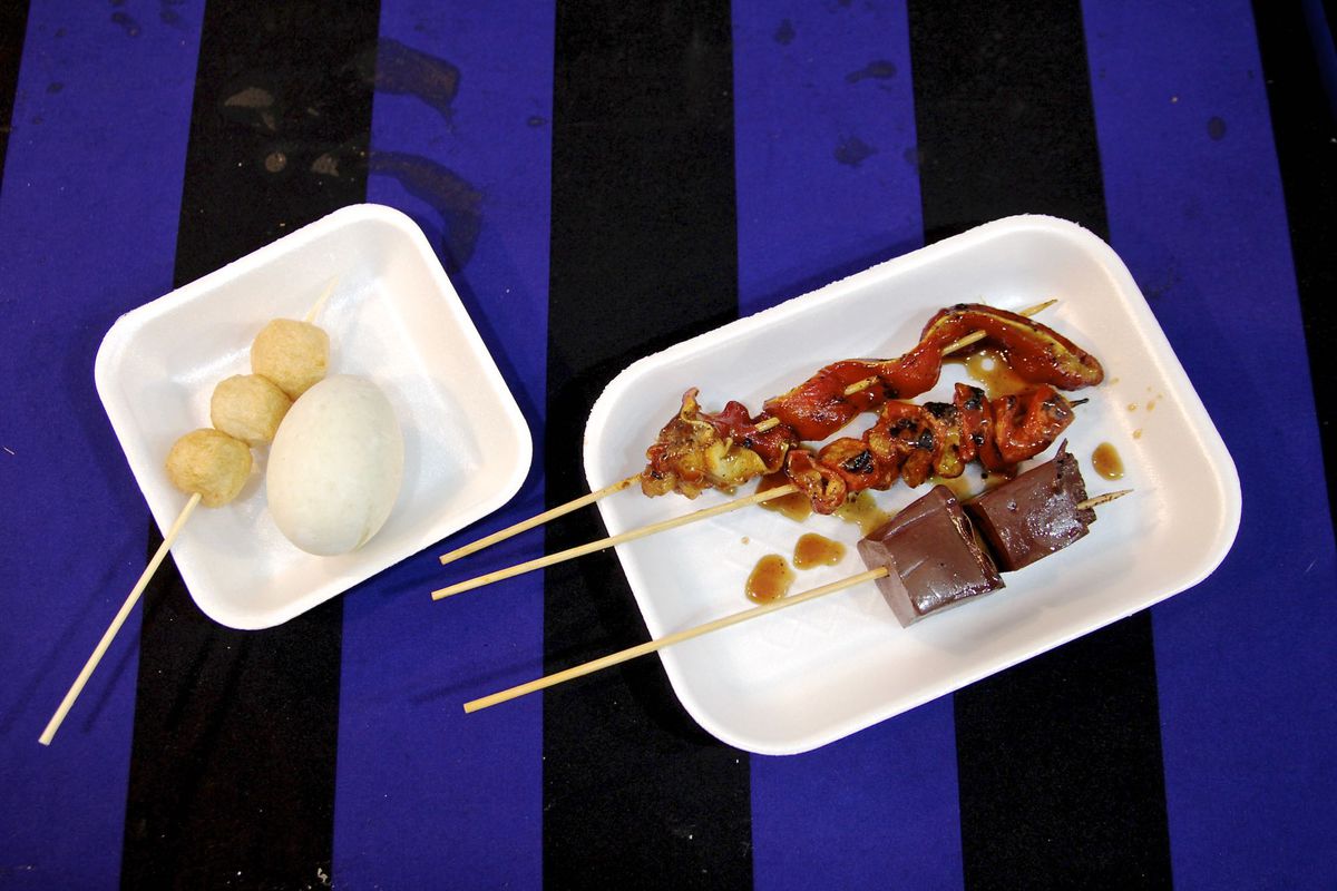 A blue striped table holds plates of meat skewers.