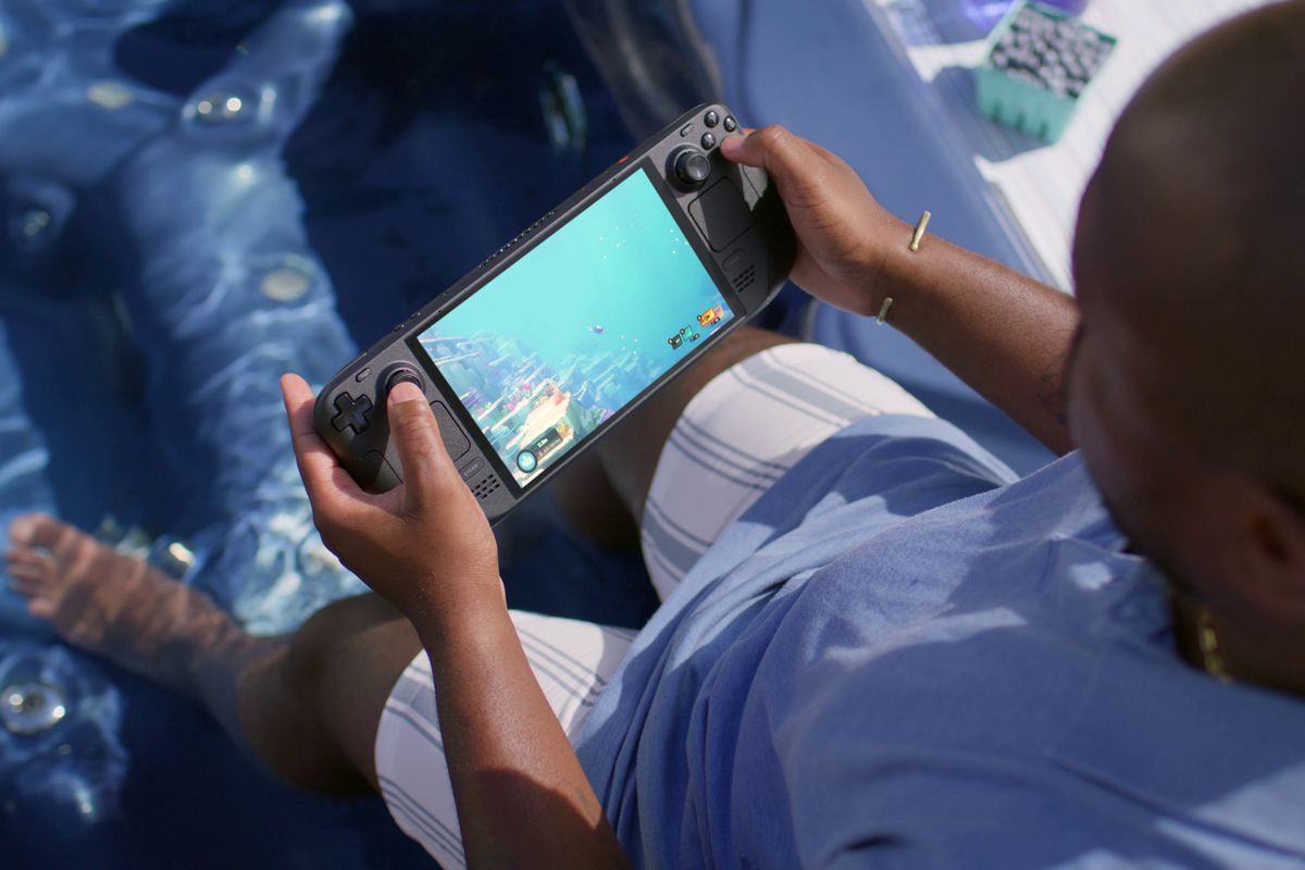A person holding the Steam Deck OLED, which is playing Dave the Diver. Ironically, the person holding the console is in a pool, thematically aligning with the fact that you’re in water in the game.