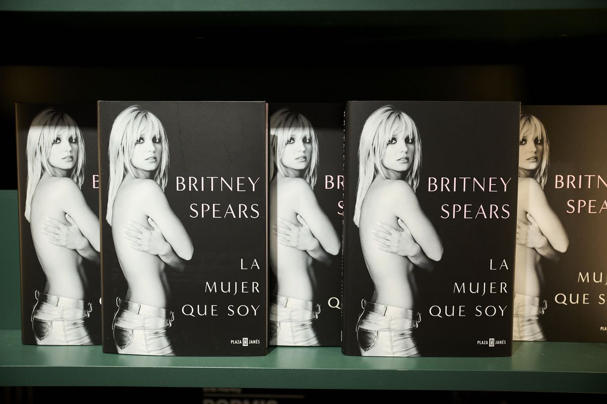 Several copies of the book “The Woman in Me,” the Britney Spears autobiography, standing on a green surface.