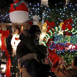 In this Dec. 14, 2016, photo, a man and his child pass Christmas decorations in the Dyker Heights neighborhood of the Brooklyn borough of New York. For years, residents in Brooklyn's Dyker Heights section have been turning their homes into a wonderland of lights, snowmen, toy soldiers, Santas and piped-in caroling. 