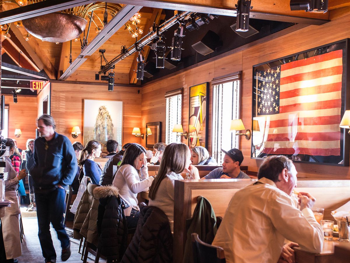 Diners in a wood-walled restaurant with large American Flag art on the wall. 
