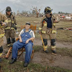 Oklahoma City firefighters check on the status of Gene Tripp as he sits in his rocking chair where his home once stood after being destroyed by a tornado that hit the area, Monday, May 20, 2013 in Oklahoma City, Okla. 