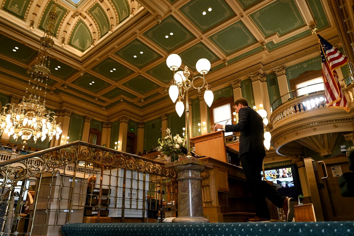 Colorado House Speaker Alec Garnett stands at the speaker’s podium with the view of the green, ornate ceiling of the House chamber in view.