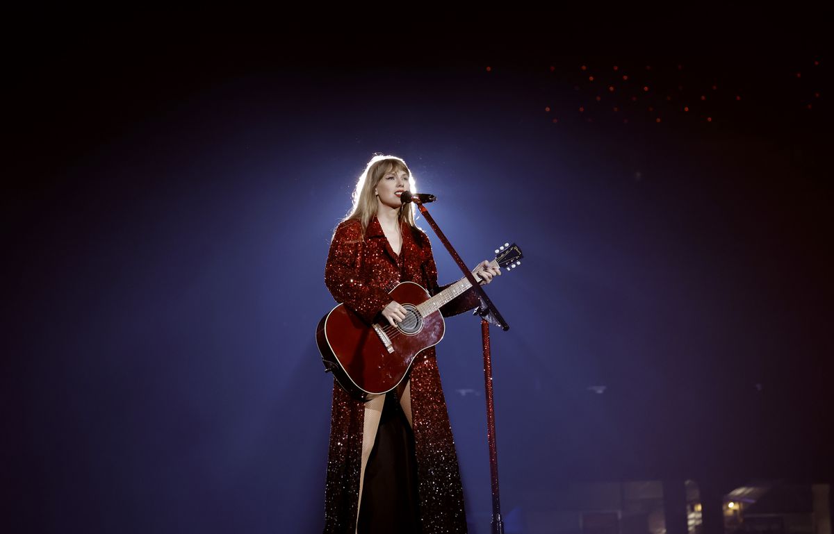 A performer in a red squined robe and outfit playing the guitar.
