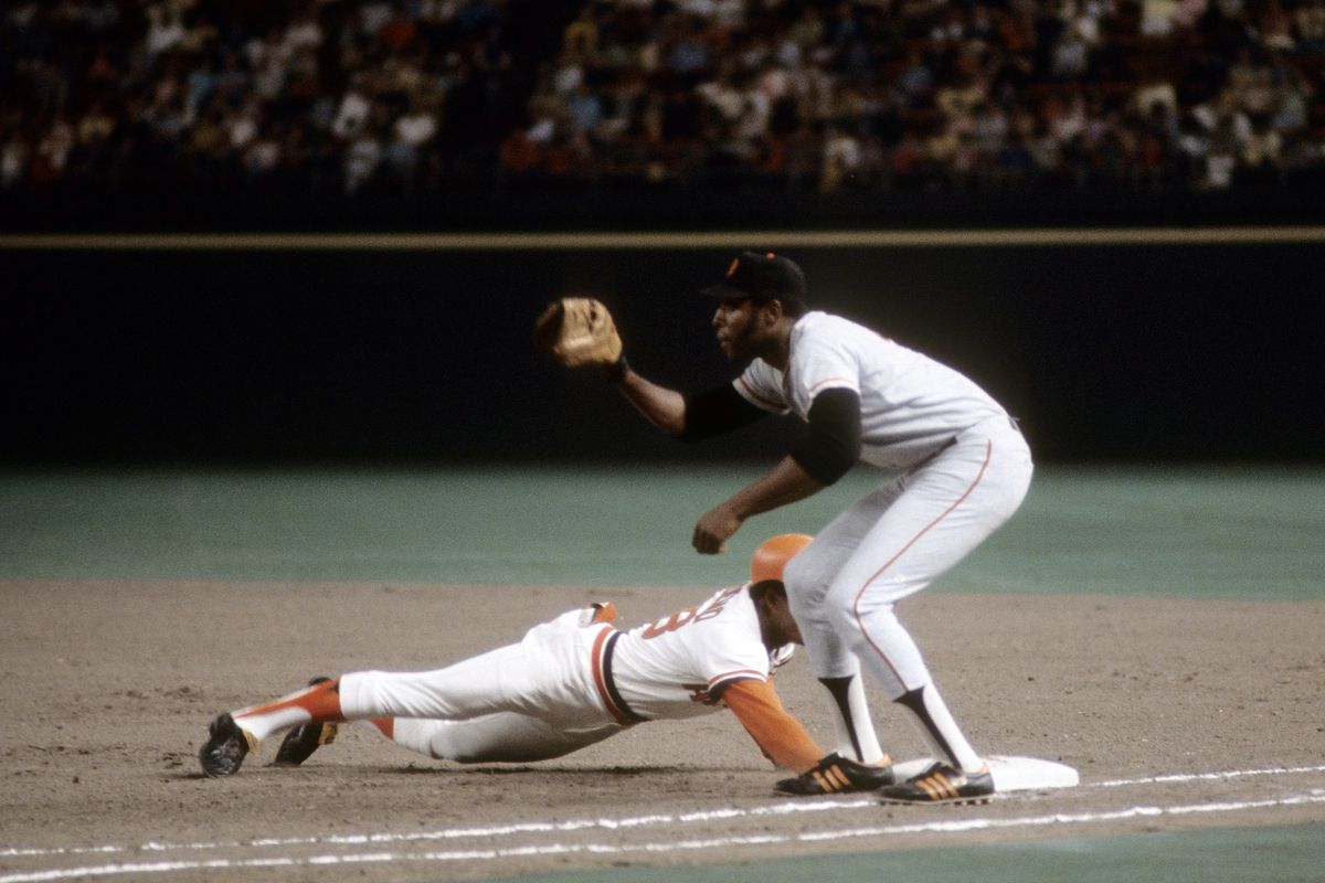 Willie McCovey catching a throw at first as a Cardinals player dives back to the bag