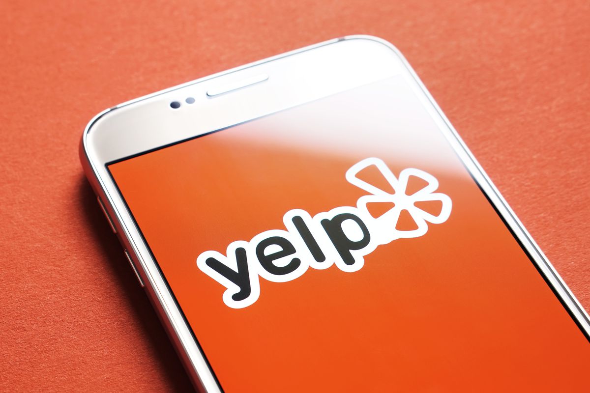 Yelp logo on a phone with red background.
