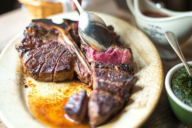 The Peter Luger porterhouse, cooked medium rare and displayed on a white plate